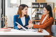 © NanSan - Two young and middle-aged Asian women lawyers in formal suits discuss legal contract, focusing on legislation and women's rights in law office.