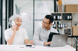 © Nuttapong punna - Two Asian  business workers talking on the smartphone and using laptop at the office.