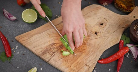 Wall Mural - Woman Cutting slicing fresh green avocado fruit with knife on a wooden board at domestic kitchen