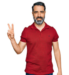 Sticker - Middle aged man with beard wearing casual red t shirt smiling with happy face winking at the camera doing victory sign. number two.