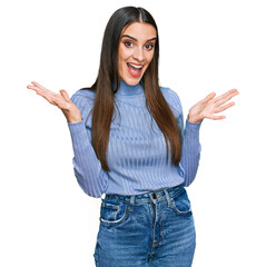 Wall Mural - Young beautiful woman wearing casual winter sweater celebrating victory with happy smile and winner expression with raised hands