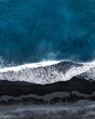 aeriel view of ocean waves on black sand beach