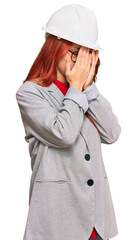 Poster - Young redhead woman wearing architect hardhat with sad expression covering face with hands while crying. depression concept.