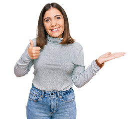 Wall Mural - Young beautiful woman wearing casual turtleneck sweater showing palm hand and doing ok gesture with thumbs up, smiling happy and cheerful