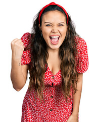 Wall Mural - Young hispanic girl wearing casual clothes angry and mad raising fist frustrated and furious while shouting with anger. rage and aggressive concept.