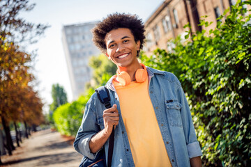 Canvas Print - Photo of positive good mood guy dressed jeans shirt headphones walking college outdoors urban city park