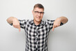 © amixstudio - Handsome man in glasses pointing down finger, demonstrating empty space for product or text isolated on white studio background.