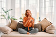 © HBS - Technology and lifestyle. Attractive woman touching chin and looking thoughtfully aside while sitting on sofa with cell phone. Blonde female with crossed legs resting at home and using modern gadget.