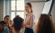 © Daniela - Woman manager in make planning in front of audience.  board during online conversation with investors at conference hall