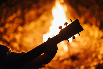 Wall Mural - Girl guitarist play the guitar near bonfire outdoor. Spending time with friends near bonfire, play the guitar