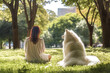 Sitting woman and samoyed dog alone in a shady park and garden tree lawn green leaves. Take your dog outside for exercise, defecating. walk with your dog to relieve loneliness. love animals pet dogs.