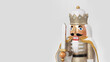 Closeup of traditional Christmas nutcracker with white clothes and cape, holding a sword, isolated on copy-space background.