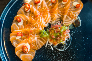 Wall Mural - Salmon with spicy sauce on black dish, top view