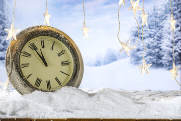 Wall Mural - Wooden retro table with clock and empty space for your product. Mockup background with snow and frost. Chrismtas tree lights. New year time in mountains. Party time in december night. 