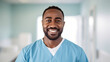 © BeautyStock - Portrait of a black nurse doctor man looking at the camera with a smile on a white bright blurred hospital background