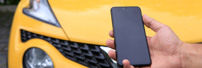 Wall Mural - Man holding phone with car in background.