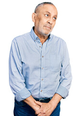 Canvas Print - Senior man with grey hair and beard wearing casual blue shirt smiling looking to the side and staring away thinking.