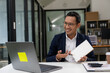 © ArLawKa - Asian businessman working at a desk business financial technology financial documents and business accounting With laptop and documents on desk, financial planning concept in office