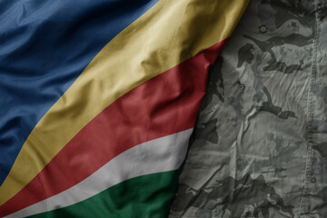 Wall Mural - waving flag of seychelles on the old khaki texture background. military concept.