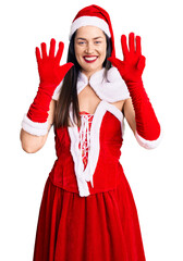 Wall Mural - Young beautiful caucasian woman wearing santa claus costume showing and pointing up with fingers number nine while smiling confident and happy.