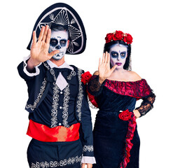 Poster - Young couple wearing mexican day of the dead costume over background doing stop sing with palm of the hand. warning expression with negative and serious gesture on the face.