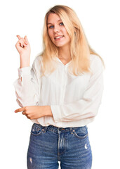 Wall Mural - Young beautiful blonde woman wearing casual shirt smiling happy pointing with hand and finger to the side