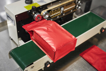 Wall Mural - Close up of red plastic bag in packaging machine at food production factory, copy space