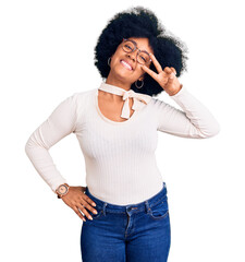 Poster - Young african american girl wearing casual clothes and glasses doing peace symbol with fingers over face, smiling cheerful showing victory