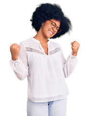 Poster - Young african american girl wearing casual clothes very happy and excited doing winner gesture with arms raised, smiling and screaming for success. celebration concept.