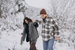 © anatoliycherkas - A young happy and loving couple walking in a snowy forest in the mountains