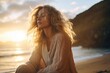 © Fotograf - A woman peacefully sits on the beach as the sun sets. Perfect for travel or relaxation-themed projects