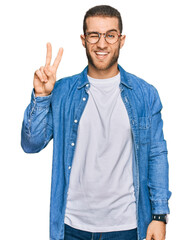 Sticker - Young caucasian man wearing casual clothes smiling with happy face winking at the camera doing victory sign with fingers. number two.