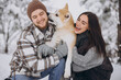 © anatoliycherkas - Happy young couple walking with akita dog in forest on winter and snowly day