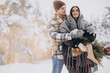 © anatoliycherkas - Cute young couple in love with pine bouquet spending time on Valentine's day in snowy winter forest in mountains