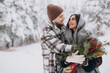 © anatoliycherkas - Cute young couple in love with pine bouquet spending time on Valentine's day in snowy winter forest in mountains