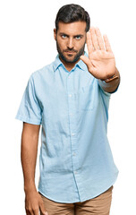 Wall Mural - Handsome hispanic man wearing casual clothes doing stop sing with palm of the hand. warning expression with negative and serious gesture on the face.