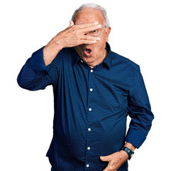 Wall Mural - Senior man with grey hair wearing casual shirt and glasses peeking in shock covering face and eyes with hand, looking through fingers with embarrassed expression.