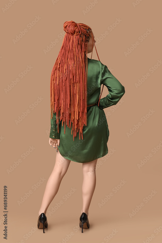 Young woman with dreadlocks on beige background, back view
