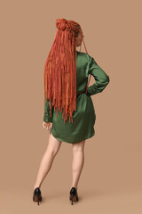 Wall Mural - Young woman with dreadlocks on beige background, back view