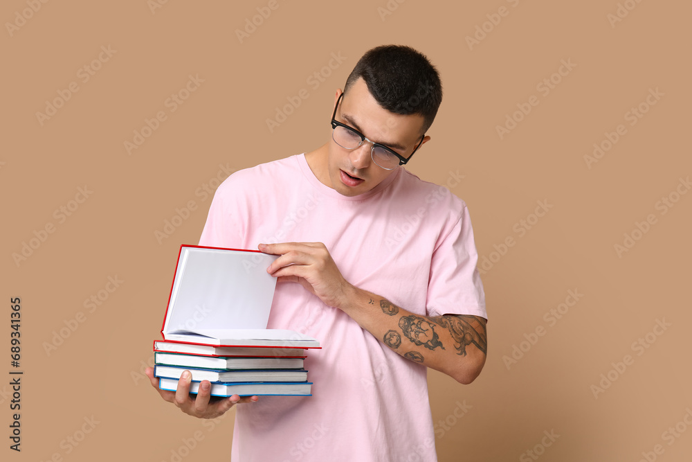 Handsome young man with books on beige background