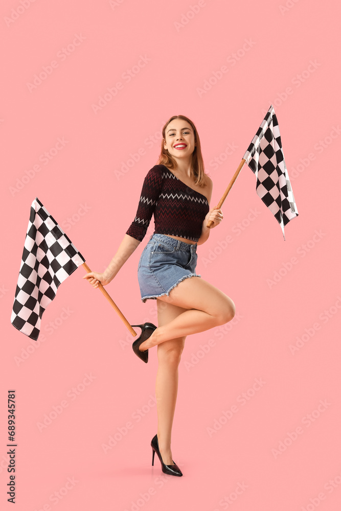 Beautiful young woman with racing flags on pink background