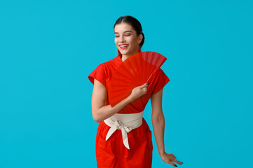 Poster - Beautiful young happy woman with fan on blue background. Chinese New Year celebration