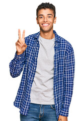 Poster - Young handsome african american man wearing casual clothes showing and pointing up with fingers number two while smiling confident and happy.