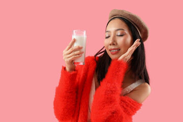 Wall Mural - Young Asian woman with glass of milk on pink background