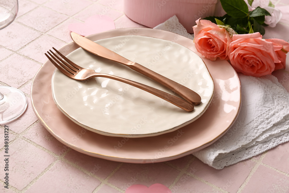 Beautiful table setting with roses for Valentine's Day on pink tile background
