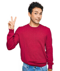 Wall Mural - Young handsome man wearing casual clothes showing and pointing up with fingers number two while smiling confident and happy.