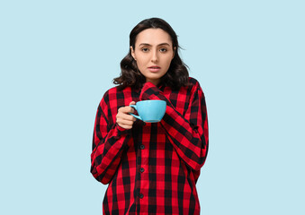 Sticker - Sick young woman with cup of tea on blue background