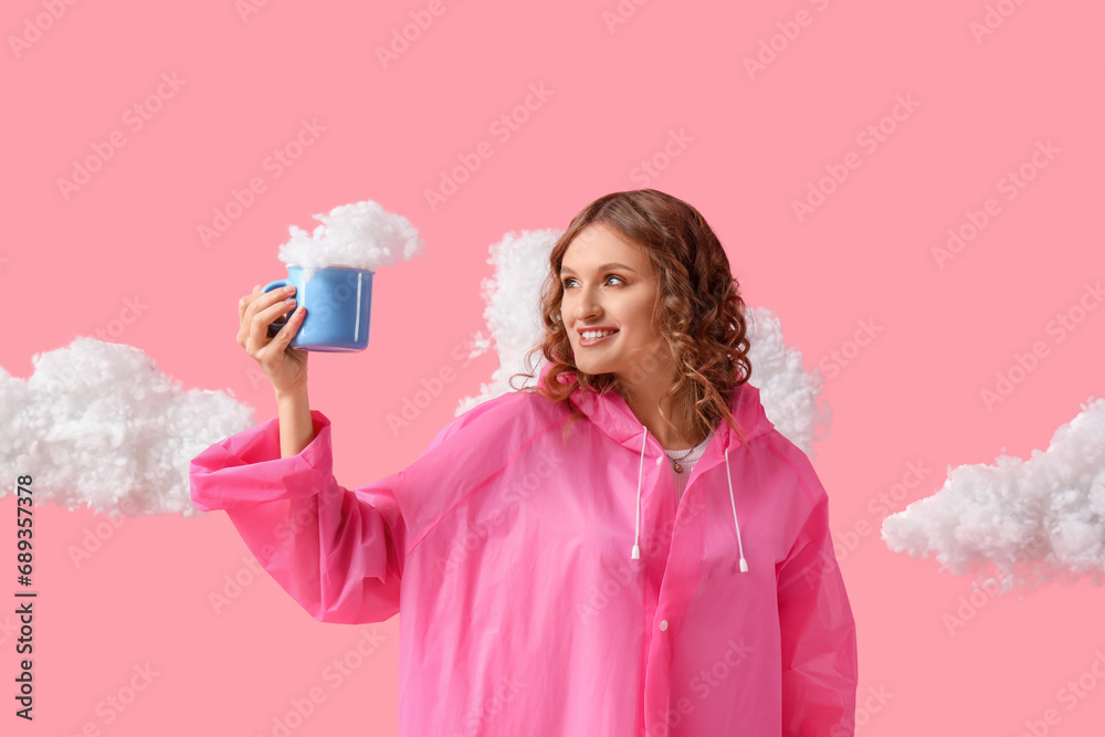 Young woman in raincoat with cup and white clouds on pink background