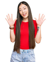 Canvas Print - Young chinese woman wearing casual clothes showing and pointing up with fingers number ten while smiling confident and happy.