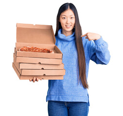 Poster - Young beautiful chinese woman holding cardboard boxes of italian pizza pointing finger to one self smiling happy and proud